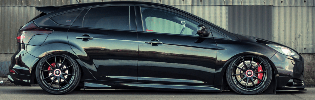 A black ford focus ST with custom tires and rims
