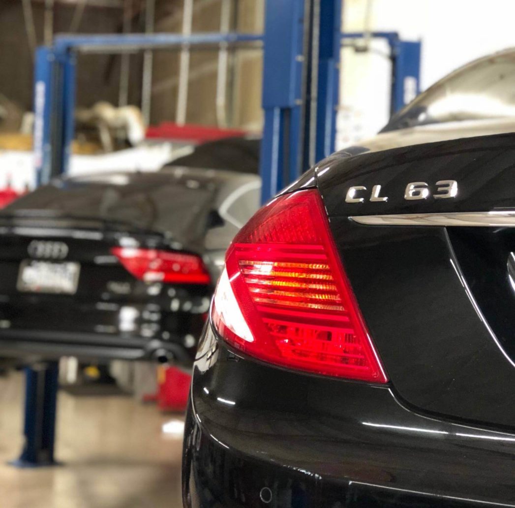 A black CL63 with an Audi on a car lift out of focus; Mercedes repair in Queen Creek, AZ at APA Auto & Fleet Care.