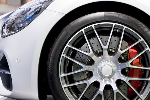 Ready to Boost Your Stopping Power with Wilwood Brakes? Call Ace Performance Automotive in Queen Creek AZ; closeup image of performance brakes seen through rims of white sports car
