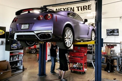 3 Simple Steps You Can Take to Help Prevent Expensive Auto Repair in Queen Creek with Ace Performance Automotive; image of purple sedan up on lift in shop bay with our 2 mechanics performing auto repair underneath