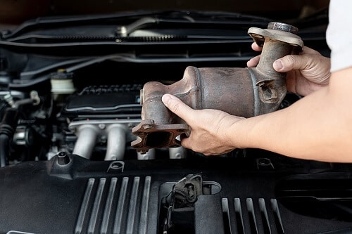 The Most Expensive Auto Repairs And How to Avoid Them | Ace Performance Auto in Queen Creek, AZ. Closeup image of an old catalytic converter in the hands of an auto technician.