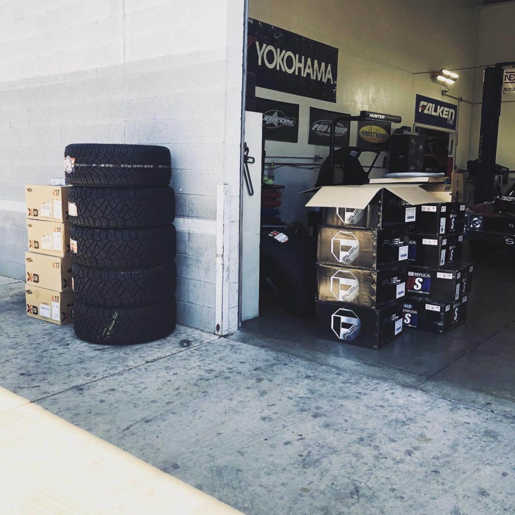 Tires sitting outside the Ace Automotive repair shop and multiple banners on a wall; Tire services in Queen Creek, AZ at APA Auto & Fleet Care.